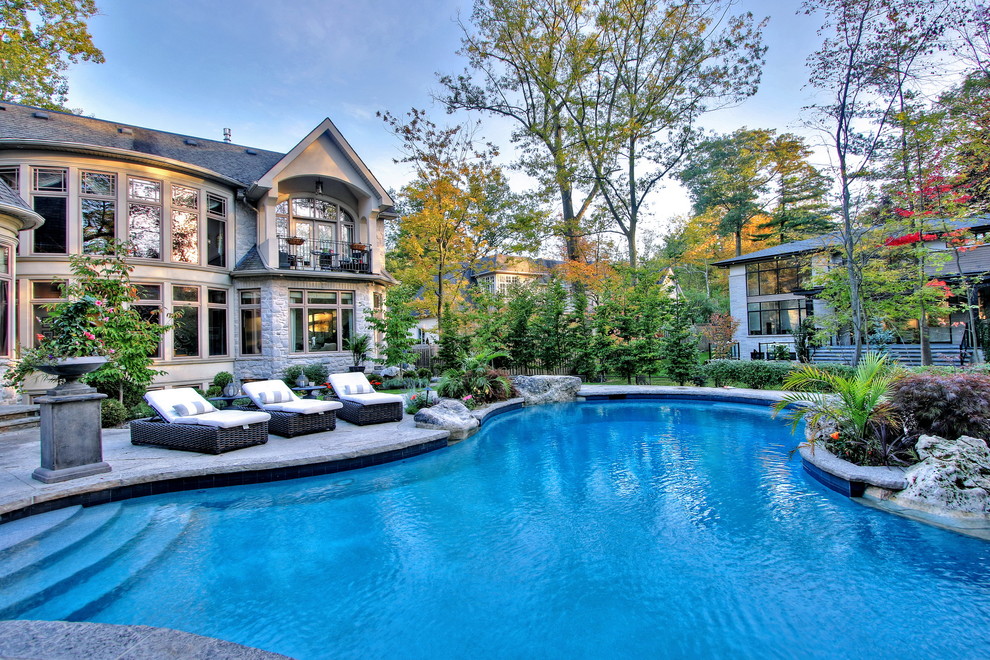 Photo of a large transitional backyard custom-shaped natural pool in Toronto with natural stone pavers.