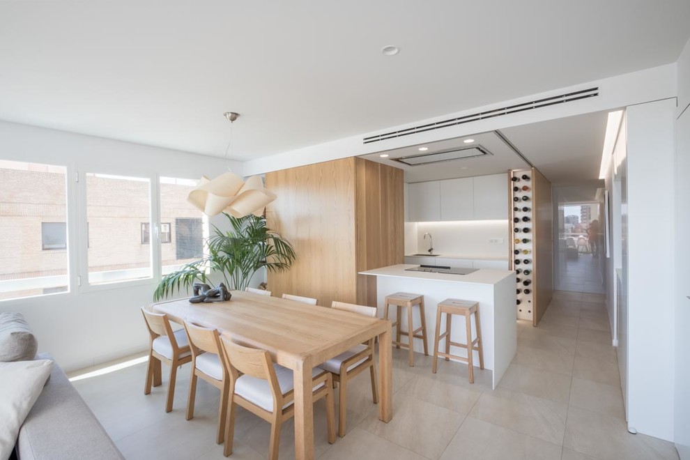 Photo of a contemporary open plan kitchen in Valencia with flat-panel cabinets, white cabinets, white splashback, a peninsula, white benchtop, a single-bowl sink and beige floor.