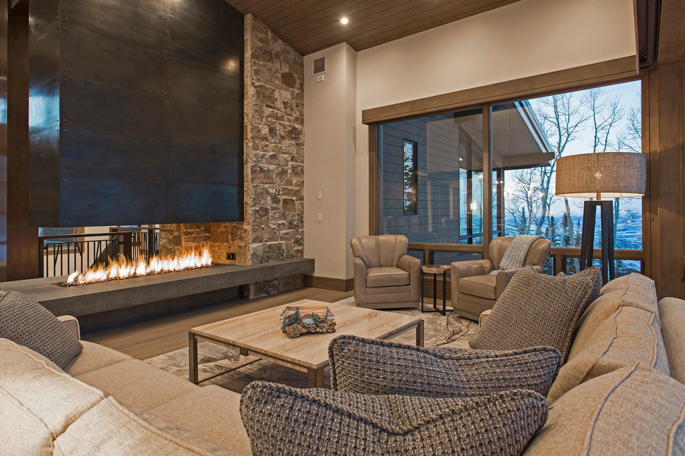 This is an example of an expansive contemporary formal open concept living room in Salt Lake City with grey walls, medium hardwood floors, a two-sided fireplace, a metal fireplace surround, no tv and wood.