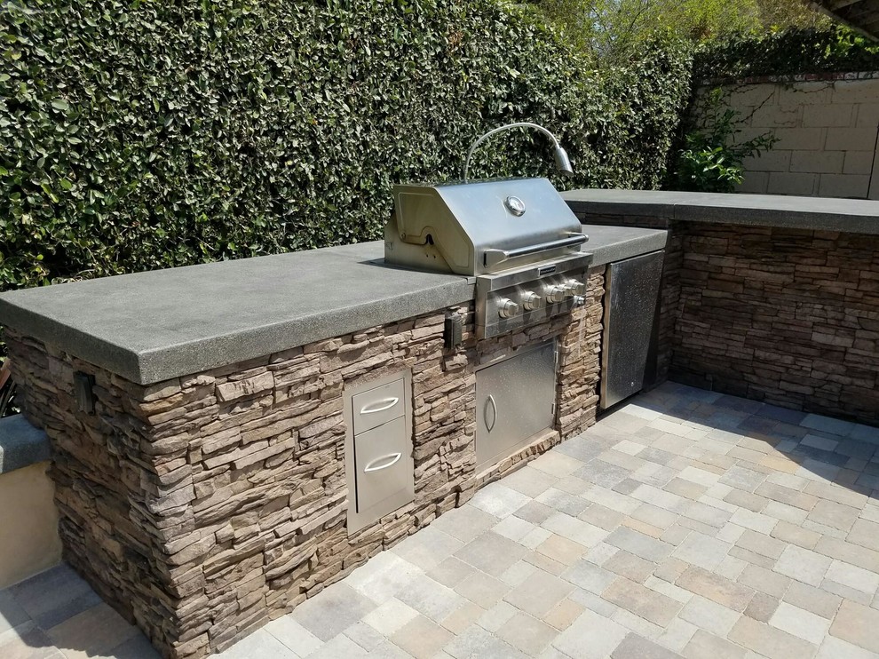 Design ideas for a tropical backyard patio in Orange County with with fireplace and concrete pavers.