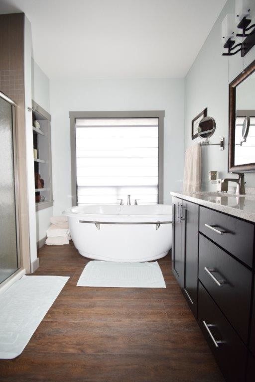 Mid-sized transitional master bathroom in Other with shaker cabinets, black cabinets, a freestanding tub, an alcove shower, grey walls, dark hardwood floors, an undermount sink, solid surface benchtops, brown floor and white benchtops.