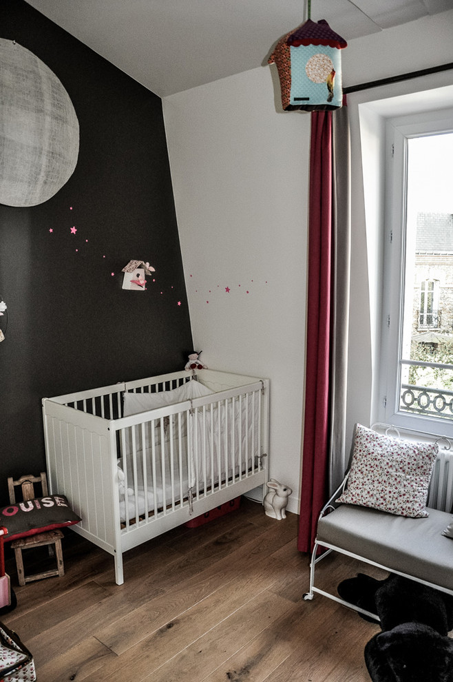 Exemple d'une grande chambre de bébé neutre tendance avec un mur noir, parquet foncé et un sol marron.