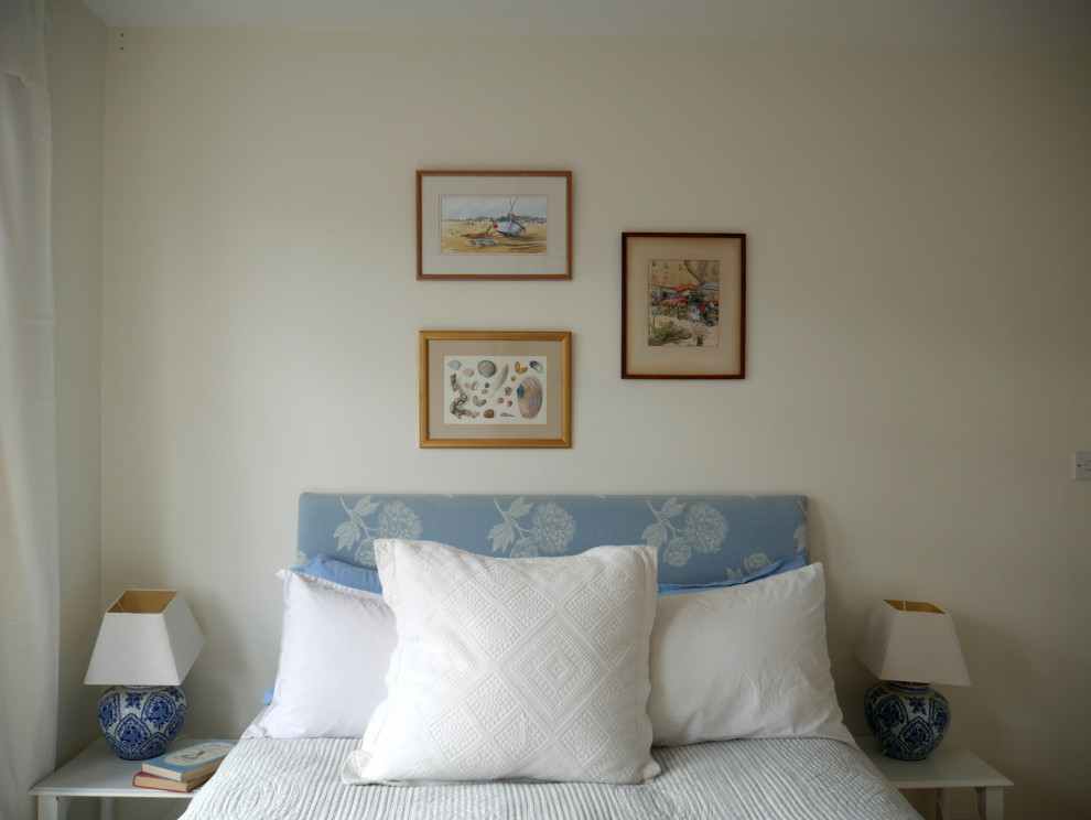 Cette photo montre une grande chambre chic avec un mur blanc, une cheminée standard, un manteau de cheminée en plâtre et un sol beige.
