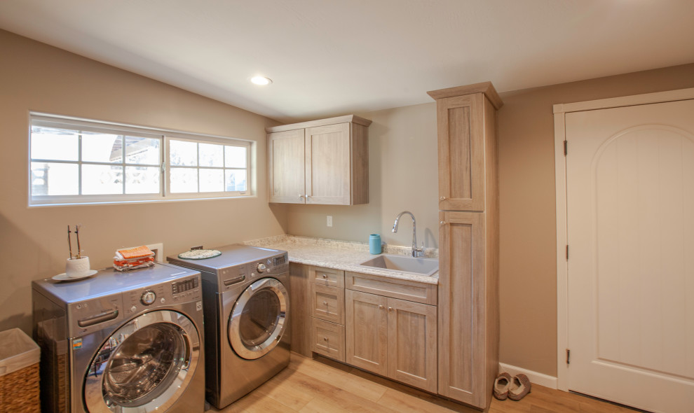 Design ideas for a midcentury laundry room in Phoenix with a drop-in sink, shaker cabinets, light wood cabinets, quartz benchtops, beige walls, laminate floors, a side-by-side washer and dryer, brown floor and multi-coloured benchtop.