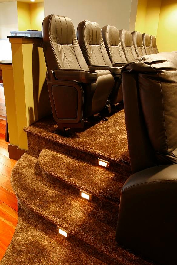 Large contemporary enclosed home theatre in Vancouver with multi-coloured walls, carpet, a projector screen and brown floor.