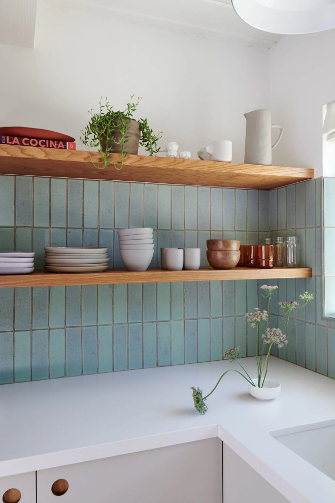 Aménagement d'une cuisine moderne avec une crédence bleue, une crédence en brique, un sol en carrelage de céramique et un sol marron.