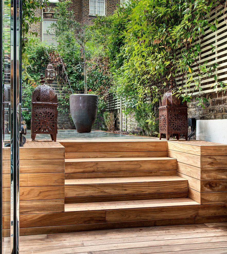 This is an example of a mid-sized asian backyard deck in London with a vertical garden.