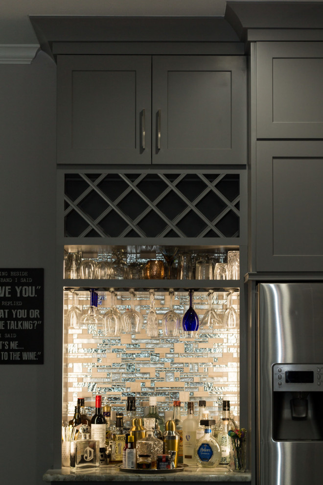 This is an example of a small contemporary single-wall home bar in Houston with shaker cabinets, grey cabinets, granite benchtops, grey splashback, glass tile splashback, porcelain floors, black floor and grey benchtop.