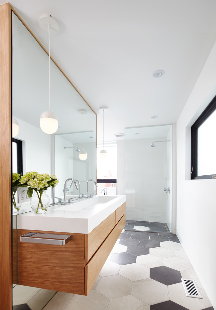 Design ideas for a mid-sized contemporary master bathroom in Toronto with flat-panel cabinets, light wood cabinets, white tile, stone tile, white walls, porcelain floors, a trough sink, solid surface benchtops, an open shower and a freestanding tub.