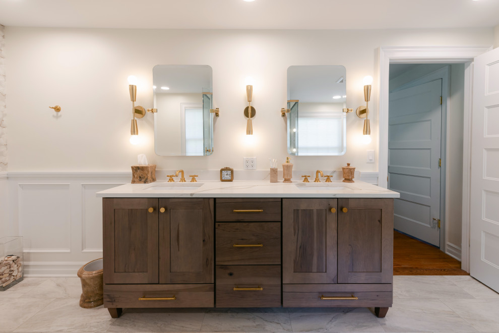 This is an example of a large transitional master bathroom in New York with shaker cabinets, light wood cabinets, a freestanding tub, an open shower, a one-piece toilet, gray tile, ceramic tile, beige walls, cement tiles, an undermount sink, engineered quartz benchtops, white floor, a hinged shower door, white benchtops, a double vanity, a freestanding vanity and decorative wall panelling.