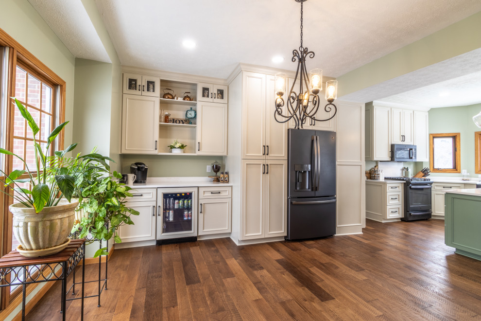 Inspiration for a large transitional l-shaped eat-in kitchen in Cleveland with a farmhouse sink, shaker cabinets, beige cabinets, quartz benchtops, black appliances, medium hardwood floors, with island, brown floor and white benchtop.