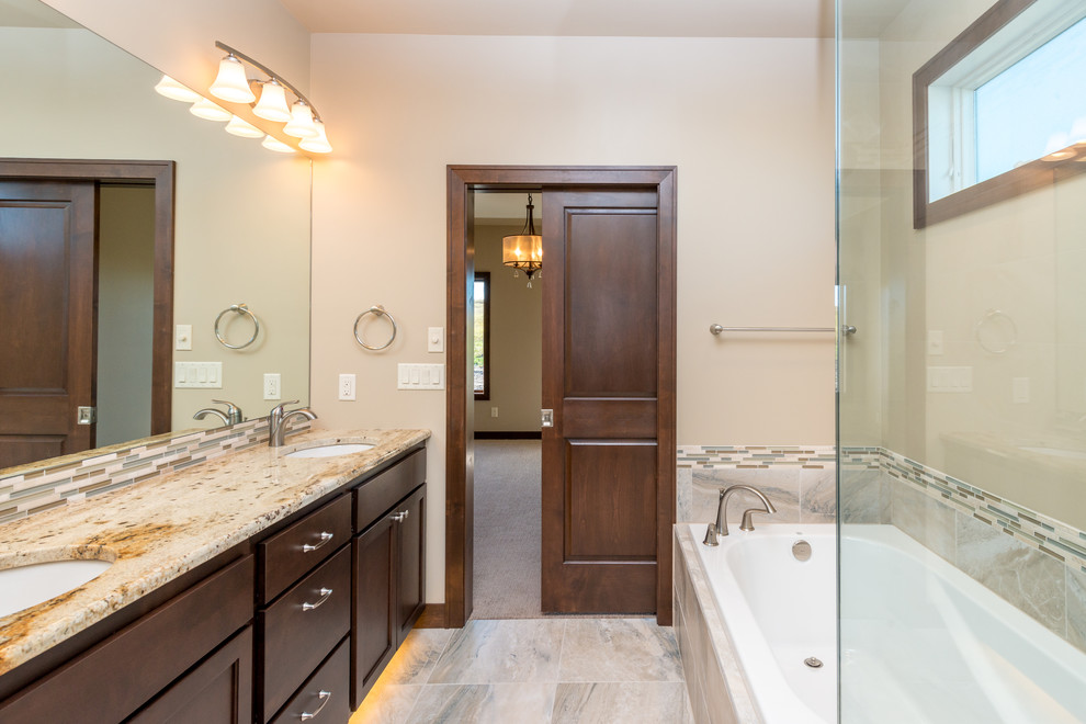 Photo of a mid-sized transitional master bathroom in Other with recessed-panel cabinets, dark wood cabinets, a drop-in tub, a corner shower, beige walls, ceramic floors, granite benchtops and an undermount sink.