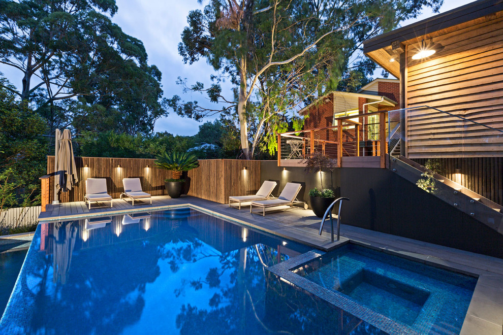 Mid-sized contemporary backyard rectangular infinity pool in Melbourne with tile.