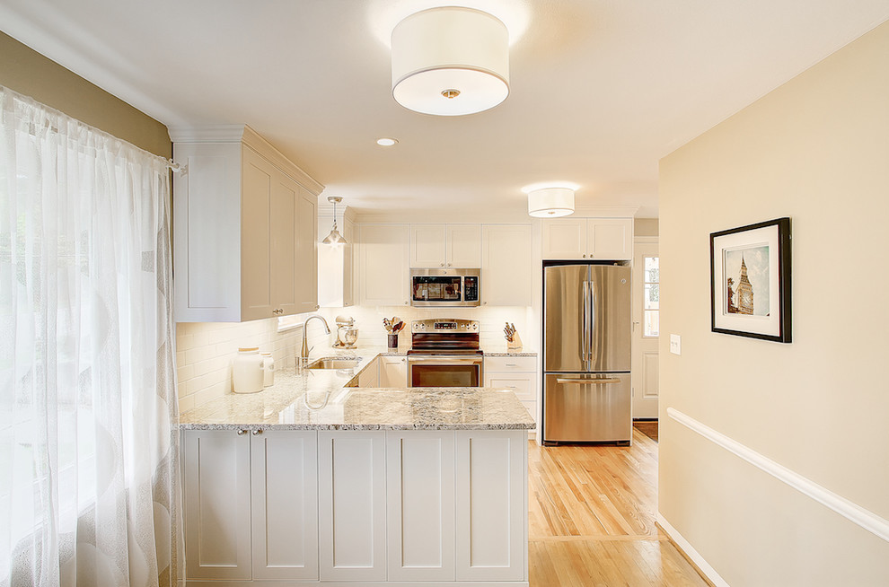 Small traditional u-shaped eat-in kitchen in Seattle with an undermount sink, shaker cabinets, white cabinets, granite benchtops, white splashback, ceramic splashback, stainless steel appliances and medium hardwood floors.