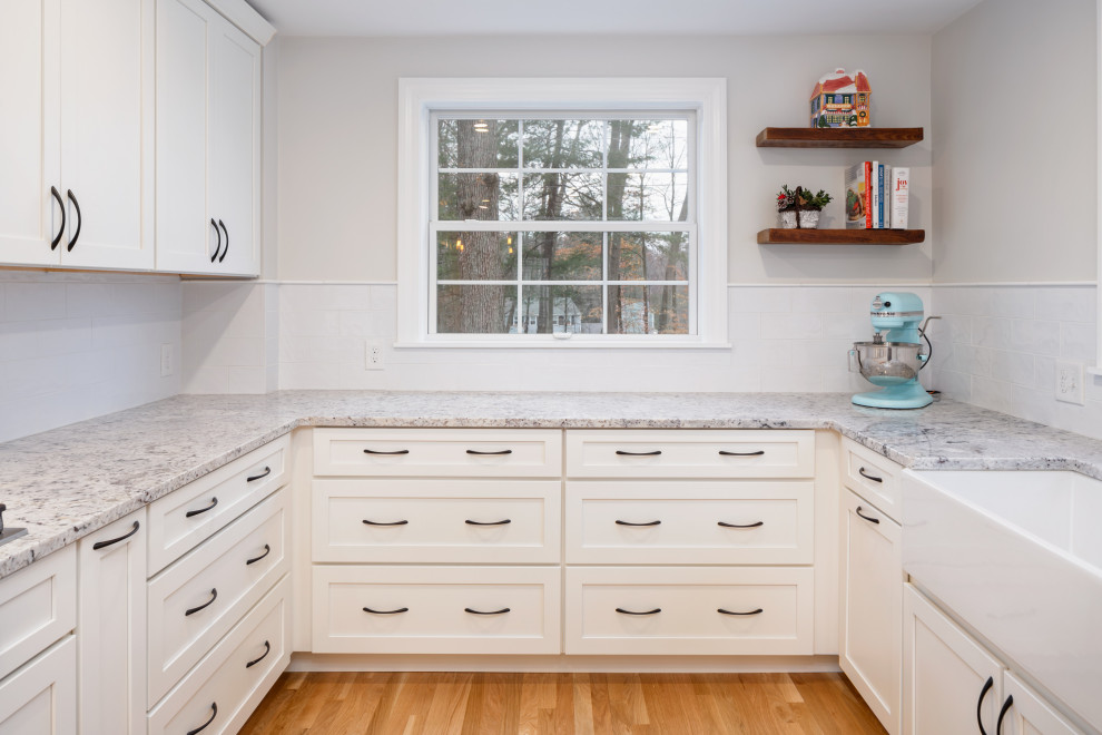 Mid-sized transitional u-shaped medium tone wood floor eat-in kitchen photo in Boston with a farmhouse sink, shaker cabinets, white cabinets, granite countertops, white backsplash, subway tile backsplash, stainless steel appliances, a peninsula and multicolored countertops