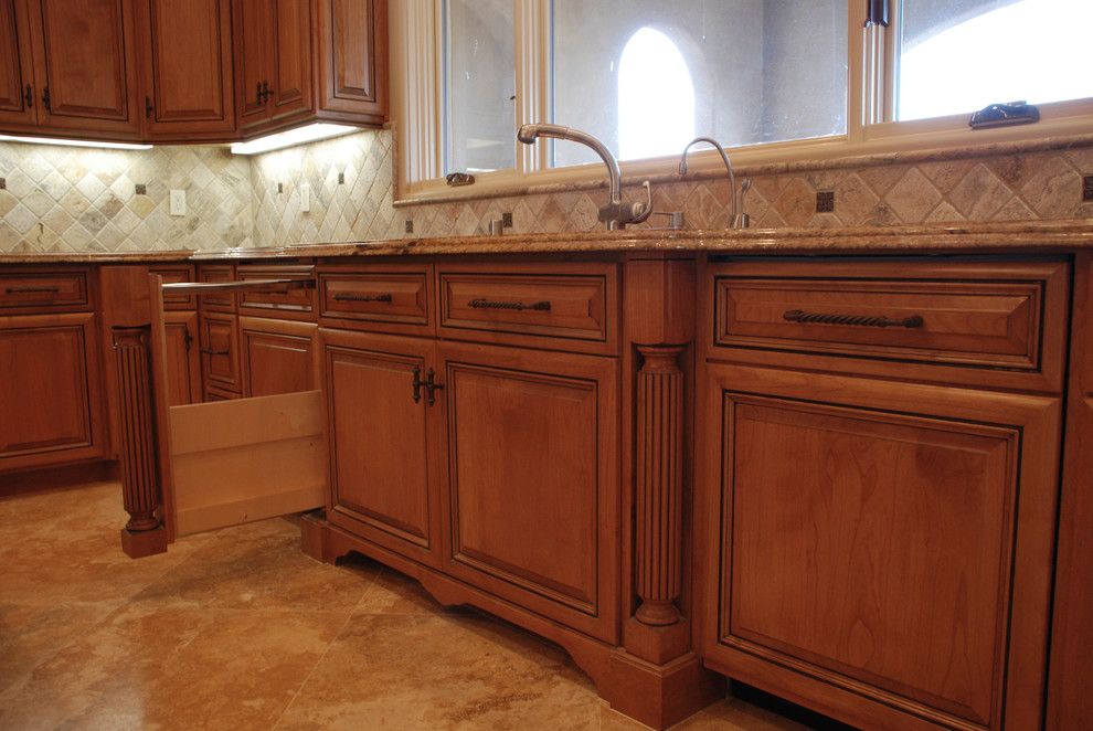 This is an example of a large traditional u-shaped kitchen in Sacramento with a double-bowl sink, raised-panel cabinets, medium wood cabinets, granite benchtops, beige splashback, stone tile splashback, panelled appliances, limestone floors and with island.