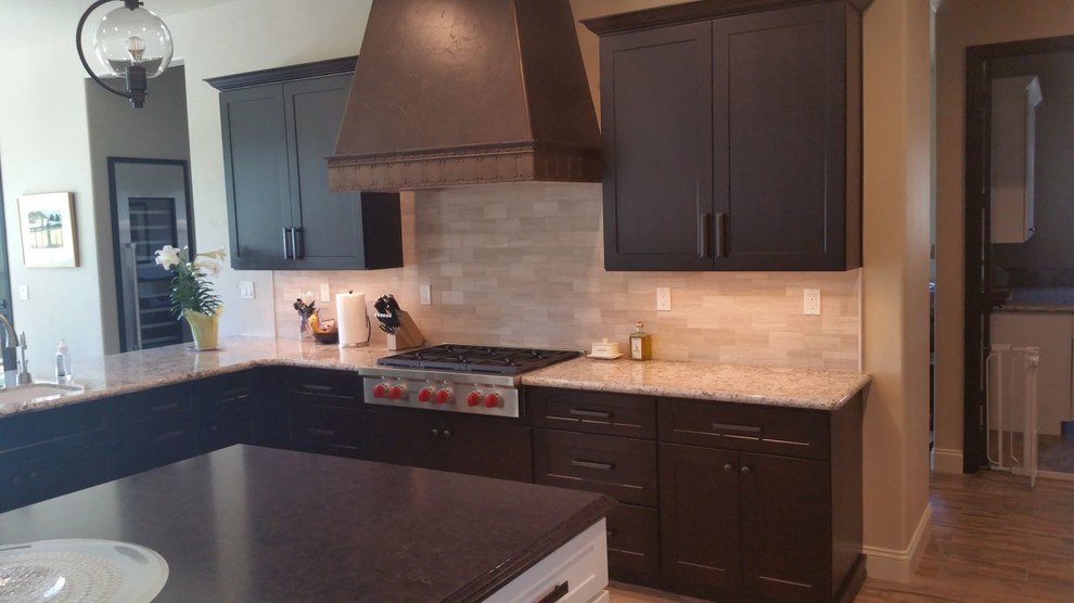 Large transitional u-shaped brown floor open concept kitchen photo with an undermount sink, recessed-panel cabinets, dark wood cabinets, granite countertops, beige backsplash, porcelain backsplash, stainless steel appliances and an island