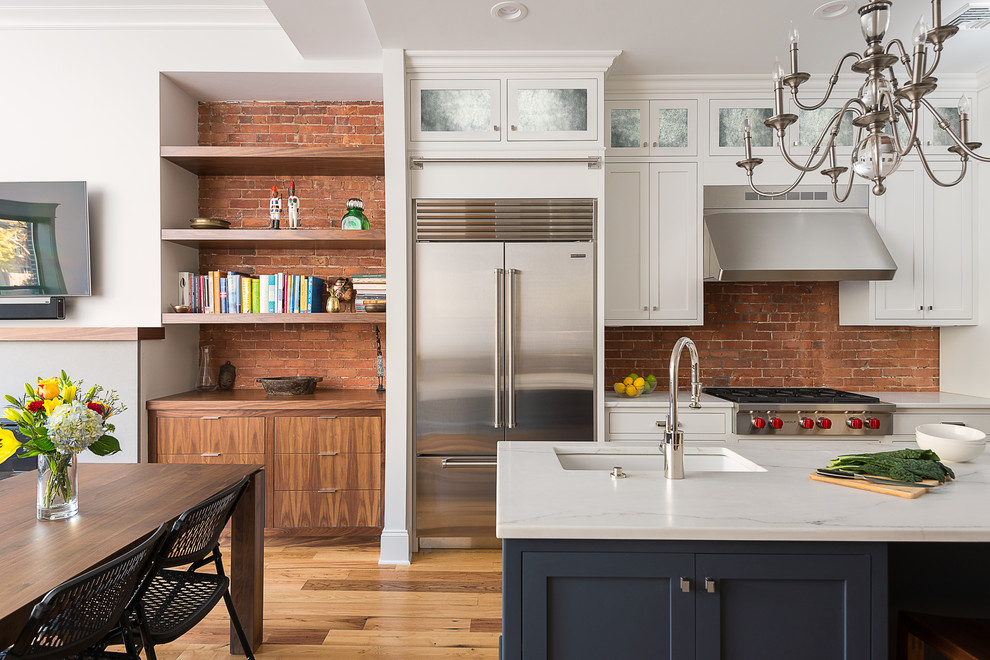 Inspiration for a mid-sized traditional l-shaped eat-in kitchen in Boston with an undermount sink, shaker cabinets, white cabinets, marble benchtops, red splashback, stainless steel appliances, medium hardwood floors and with island.