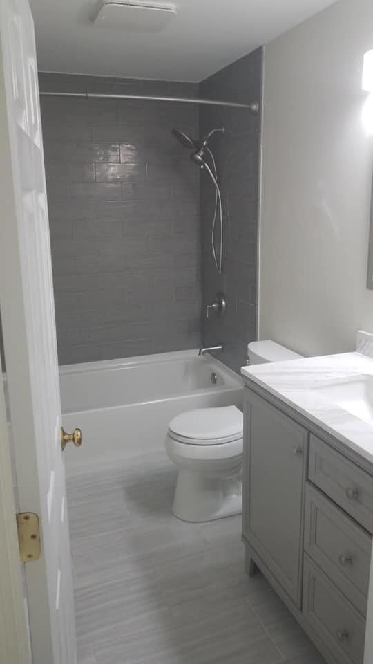 Bild på ett mellanstort vintage flerfärgad flerfärgat badrum, med grå skåp, en dusch/badkar-kombination, en toalettstol med hel cisternkåpa, grå kakel, glaskakel, ett undermonterad handfat, marmorbänkskiva och med dusch som är öppen