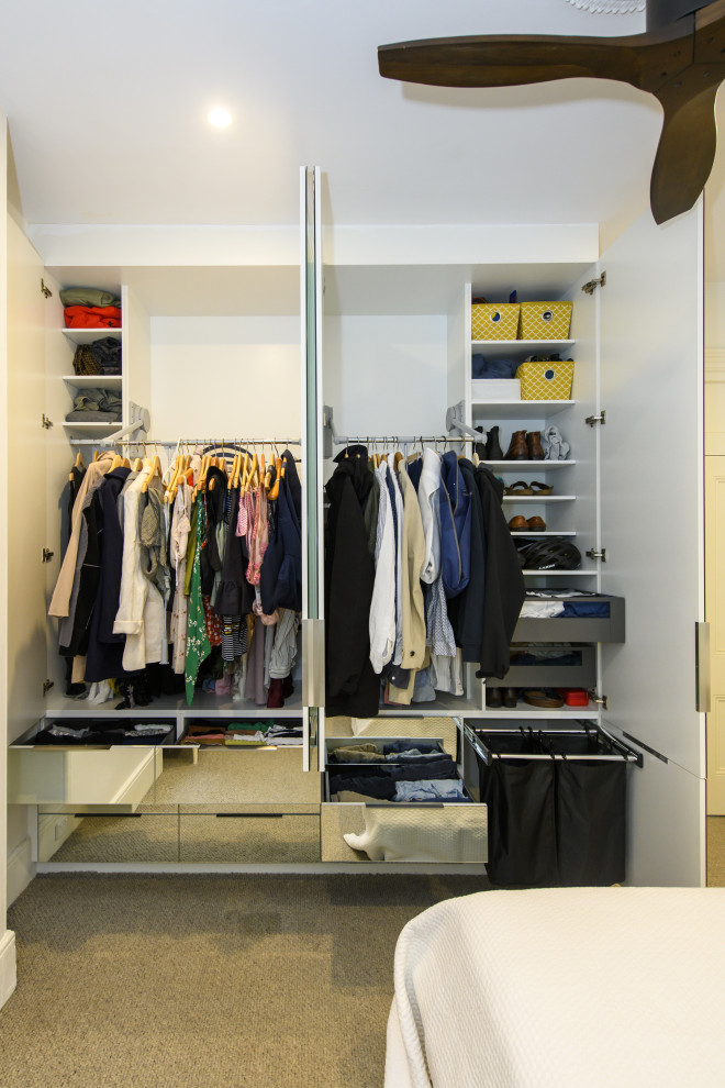 Photo of a medium sized modern gender neutral wardrobe in Sydney with glass-front cabinets, white cabinets and beige floors.