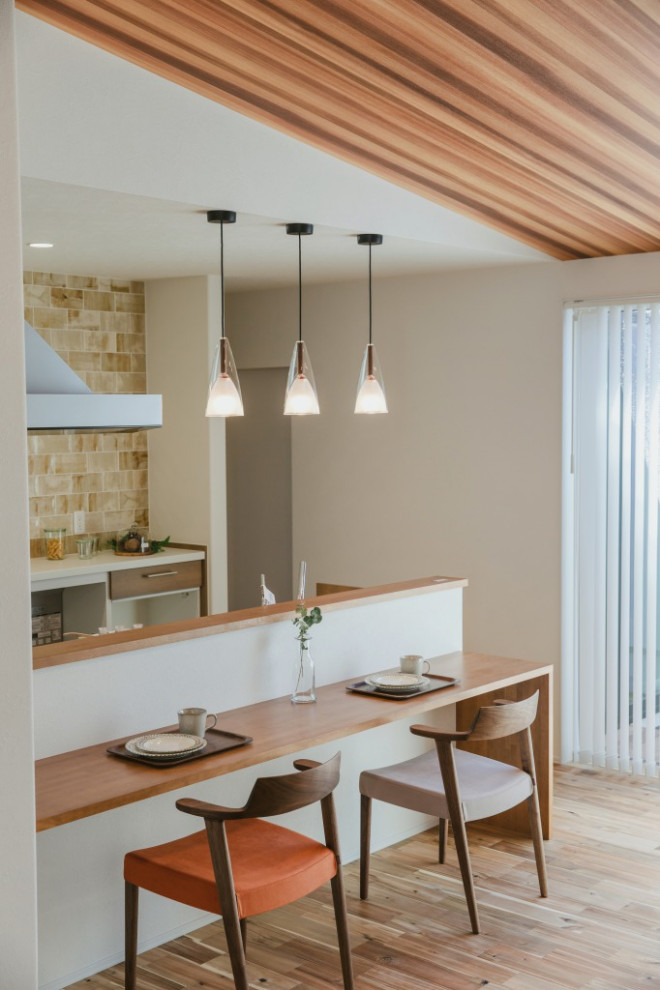 Exemple d'une cuisine ouverte parallèle tendance avec des portes de placard blanches, une crédence blanche, un sol en bois brun, un sol marron, un plan de travail beige et un plafond en bois.