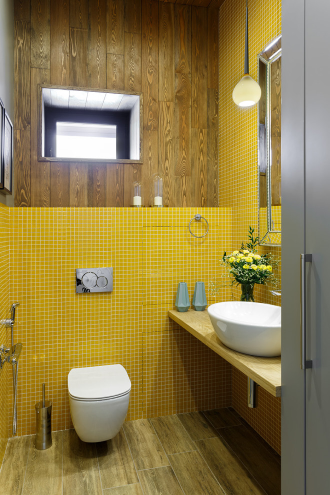 Пример оригинального дизайна: маленький туалет в современном стиле с инсталляцией, разноцветной плиткой, разноцветными стенами, полом из керамогранита, настольной раковиной, столешницей из дерева, коричневым полом, коричневой столешницей, акцентной стеной, стенами из вагонки и стеклянной плиткой для на участке и в саду