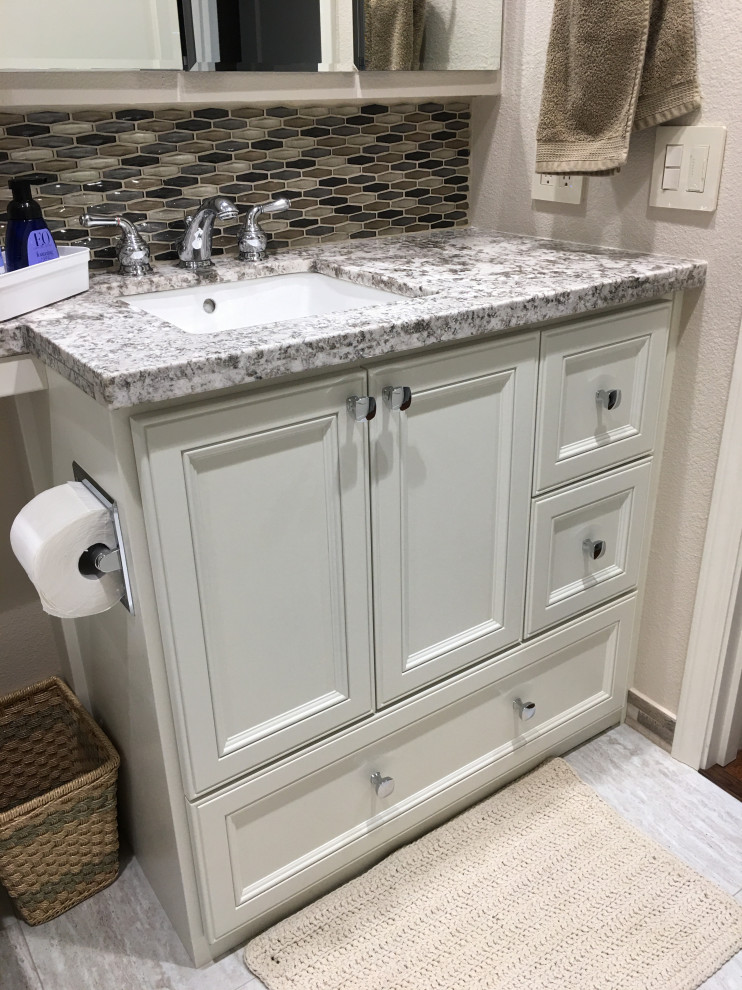 Photo of a mid-sized traditional bathroom in Portland with raised-panel cabinets, white cabinets, an alcove tub, a shower/bathtub combo, a two-piece toilet, beige tile, stone tile, beige walls, linoleum floors, an undermount sink, granite benchtops, grey floor, a sliding shower screen, grey benchtops, a niche, a single vanity and a built-in vanity.