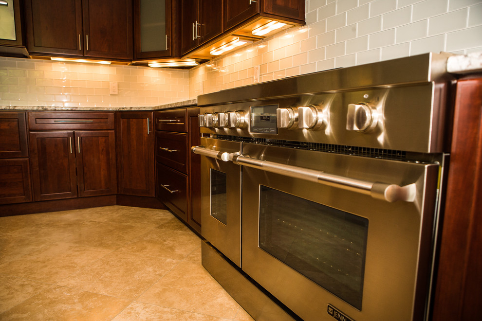 This is an example of an expansive transitional u-shaped eat-in kitchen in DC Metro with an undermount sink, dark wood cabinets, granite benchtops, glass tile splashback, stainless steel appliances, marble floors and with island.