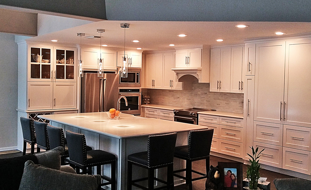 Large transitional l-shaped medium tone wood floor and brown floor open concept kitchen photo in Houston with a farmhouse sink, shaker cabinets, white cabinets, quartz countertops, white backsplash, marble backsplash, stainless steel appliances and an island