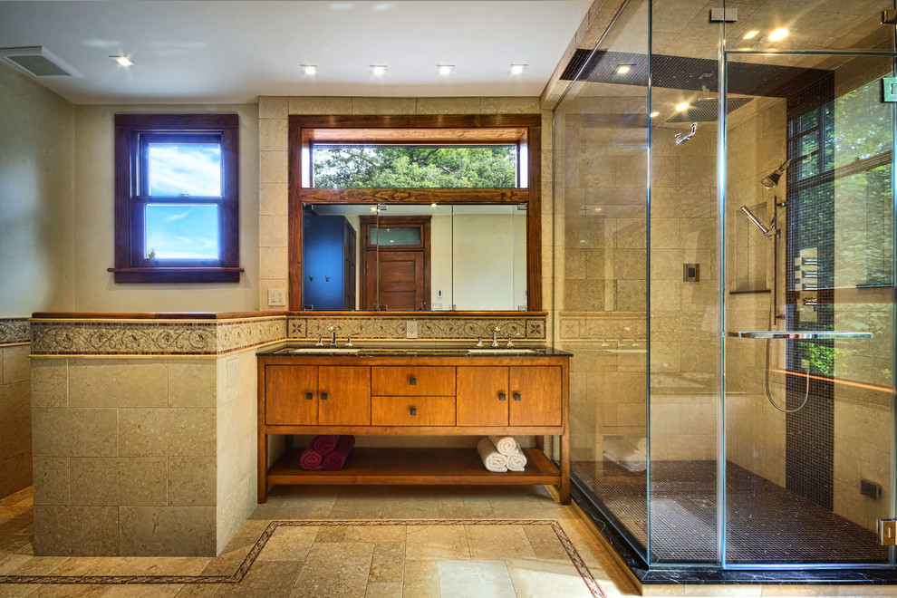 This is an example of a large modern bathroom in New York with an undermount sink, furniture-like cabinets, medium wood cabinets, marble benchtops, an undermount tub, a two-piece toilet, brown tile, stone tile, brown walls and limestone floors.