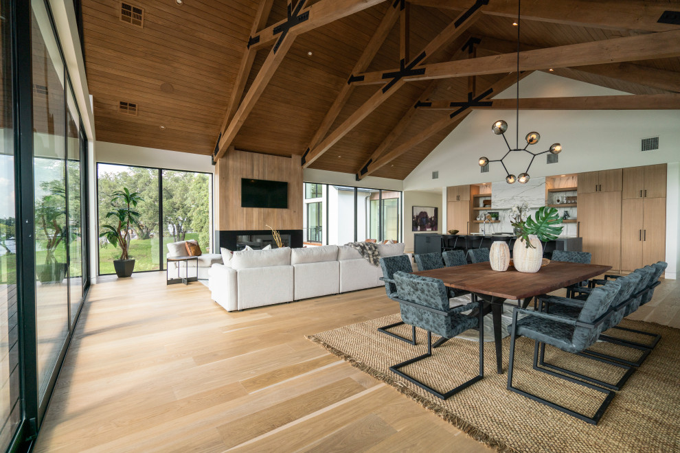 Offenes Modernes Esszimmer mit weißer Wandfarbe, hellem Holzboden, beigem Boden, freigelegten Dachbalken, gewölbter Decke und Holzdecke in Austin