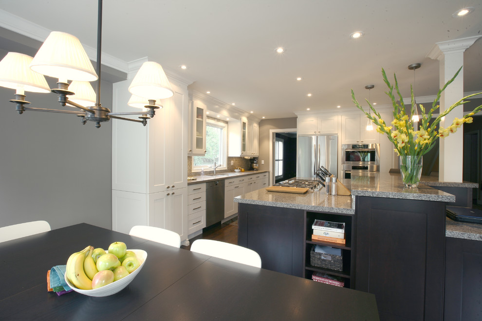 Inspiration for a large transitional l-shaped kitchen pantry remodel in Toronto with a double-bowl sink, shaker cabinets, white cabinets, granite countertops, beige backsplash, stone tile backsplash, stainless steel appliances and an island