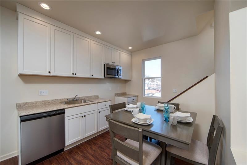 Small transitional galley brown floor eat-in kitchen photo with a single-bowl sink, shaker cabinets, white cabinets, laminate countertops, stainless steel appliances and no island