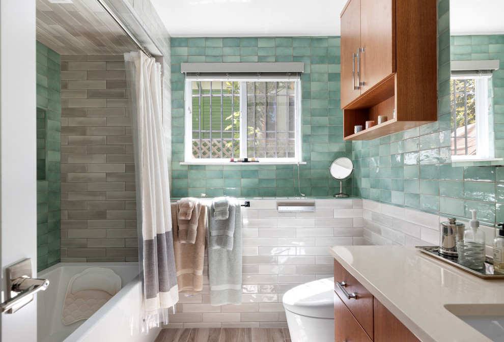 Cette photo montre une salle de bain chic en bois brun de taille moyenne avec un placard à porte plane, une baignoire en alcôve, un combiné douche/baignoire, WC suspendus, un carrelage vert, des carreaux de céramique, un mur multicolore, un sol en carrelage de porcelaine, un lavabo encastré, un plan de toilette en quartz modifié, un sol marron, un plan de toilette beige, meuble simple vasque et meuble-lavabo encastré.