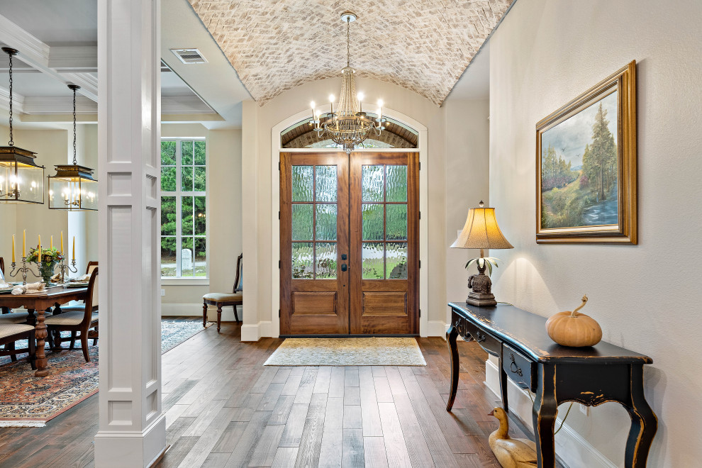 This is an example of an entryway in Houston with dark hardwood floors and a double front door.