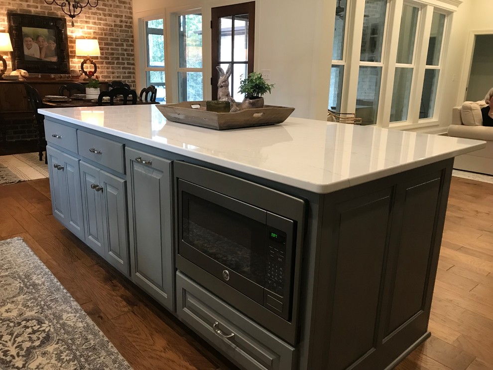 Inspiration for a large transitional l-shaped dark wood floor and brown floor open concept kitchen remodel with a double-bowl sink, raised-panel cabinets, gray cabinets, white backsplash, subway tile backsplash, stainless steel appliances, an island and white countertops