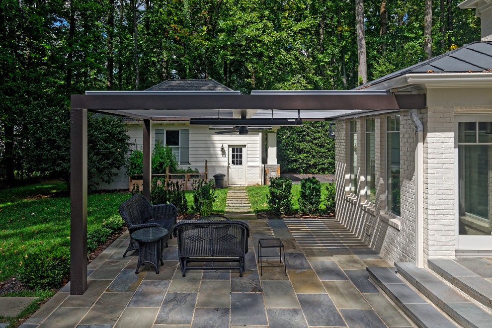 This is an example of a transitional backyard patio in DC Metro with natural stone pavers and a pergola.
