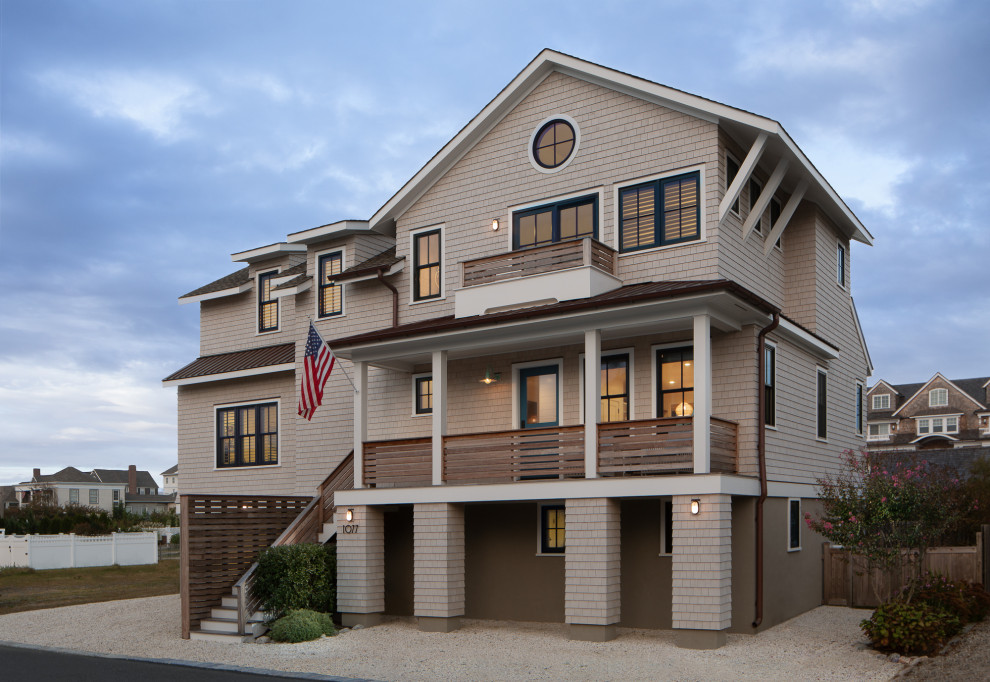 This is an example of a mid-sized beach style three-storey beige house exterior in New York with wood siding, a gable roof, a shingle roof, a brown roof and shingle siding.