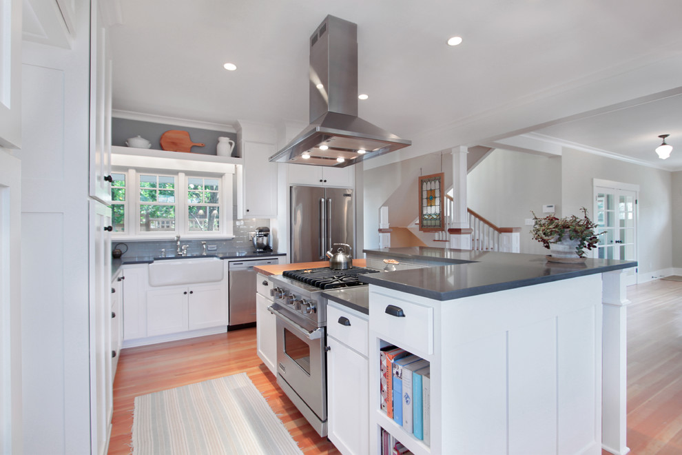 Photo of a mid-sized arts and crafts l-shaped eat-in kitchen in Seattle with an undermount sink, shaker cabinets, white cabinets, quartzite benchtops, white splashback, glass tile splashback, stainless steel appliances, medium hardwood floors, with island, brown floor and grey benchtop.