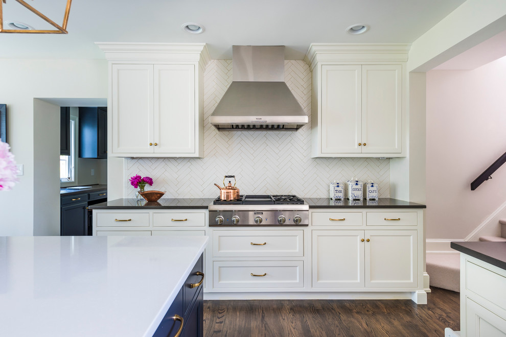 Example of a large transitional u-shaped dark wood floor and brown floor kitchen design in Philadelphia with white cabinets, quartz countertops, white backsplash, ceramic backsplash, stainless steel appliances, an island, a farmhouse sink and shaker cabinets
