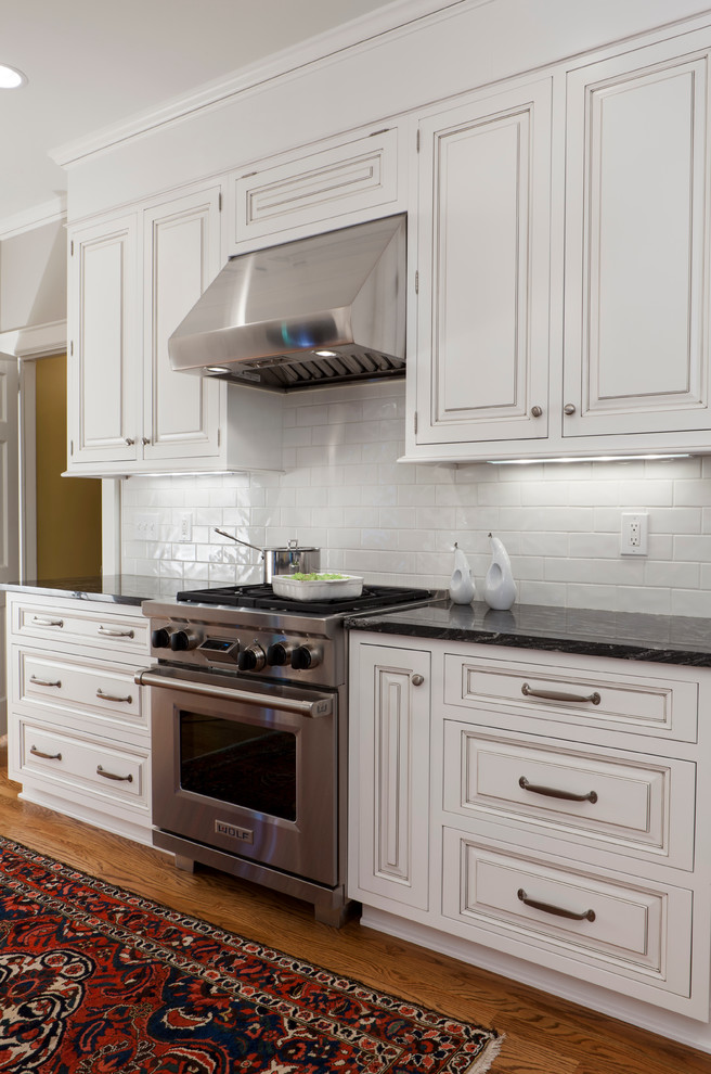 Inspiration for a traditional galley kitchen in Charlotte with an undermount sink, raised-panel cabinets, white cabinets, granite benchtops, white splashback, cement tile splashback and stainless steel appliances.