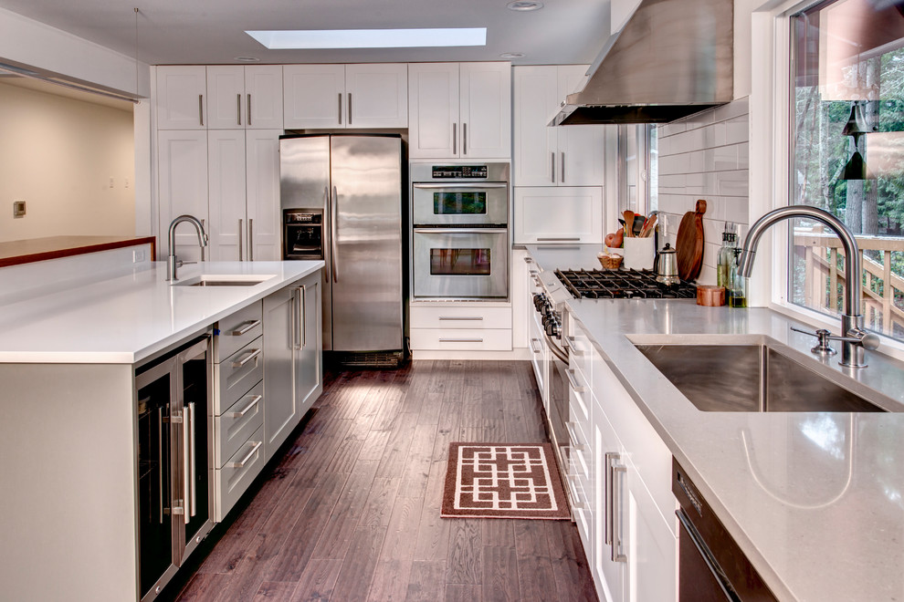 Open concept kitchen - transitional l-shaped medium tone wood floor open concept kitchen idea in Seattle with an undermount sink, shaker cabinets, white cabinets, quartz countertops, white backsplash, subway tile backsplash, stainless steel appliances and an island