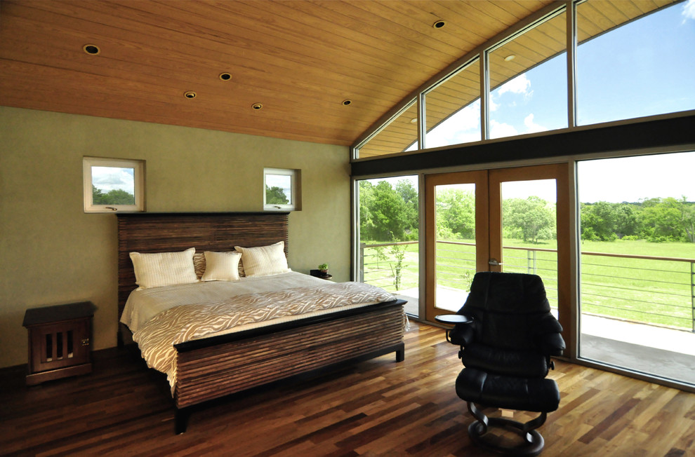 Large contemporary master bedroom in Houston with green walls, dark hardwood floors, no fireplace and brown floor.