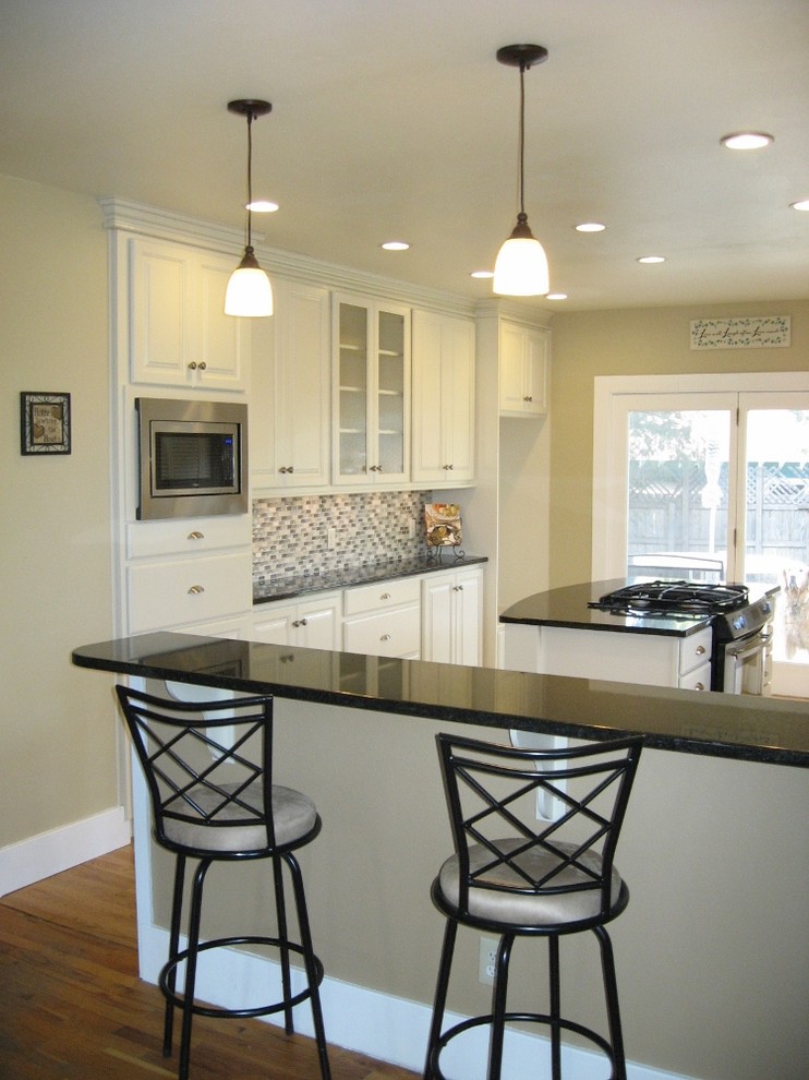 Inspiration for a mid-sized transitional u-shaped dark wood floor enclosed kitchen remodel in Denver with raised-panel cabinets, white cabinets, quartzite countertops, multicolored backsplash, matchstick tile backsplash, stainless steel appliances, an island and an undermount sink