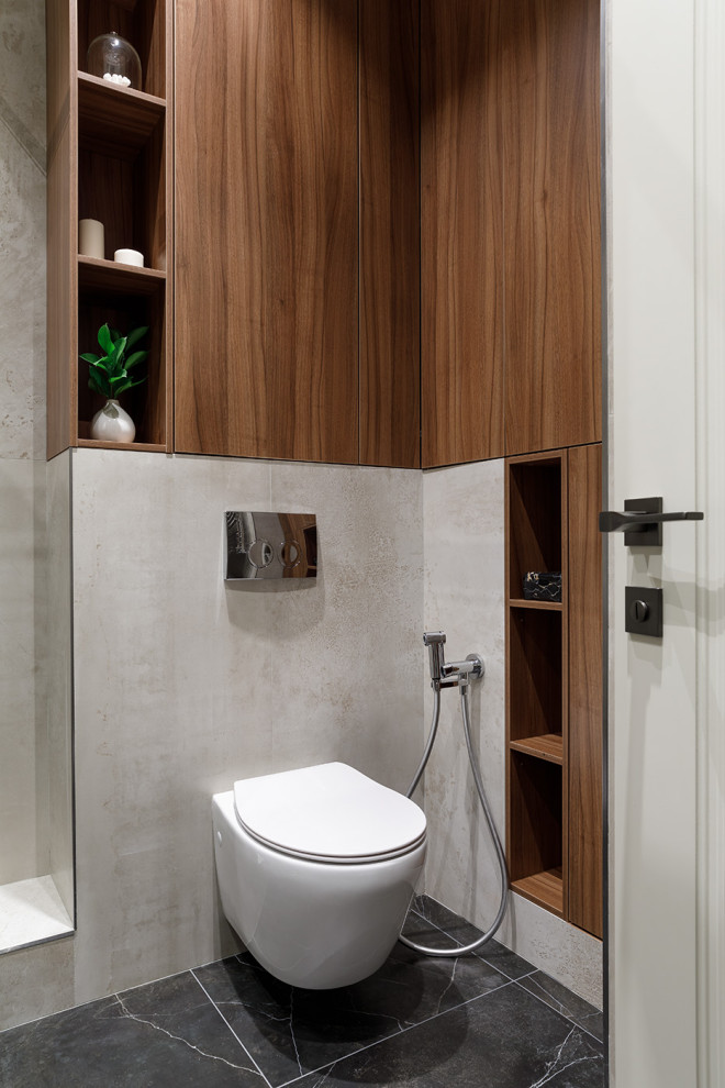 Пример оригинального дизайна: ванная комната среднего размера в современном стиле с плоскими фасадами, коричневыми фасадами, угловым душем, инсталляцией, бежевой плиткой, керамогранитной плиткой, бежевыми стенами, полом из керамогранита, душевой кабиной, монолитной раковиной, столешницей из искусственного камня, черным полом, душем с распашными дверями, белой столешницей, гигиеническим душем, тумбой под одну раковину и подвесной тумбой