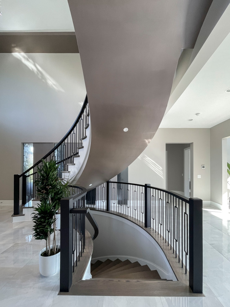 Ejemplo de escalera curva clásica renovada extra grande con escalones de madera, contrahuellas de madera pintada, barandilla de varios materiales y papel pintado