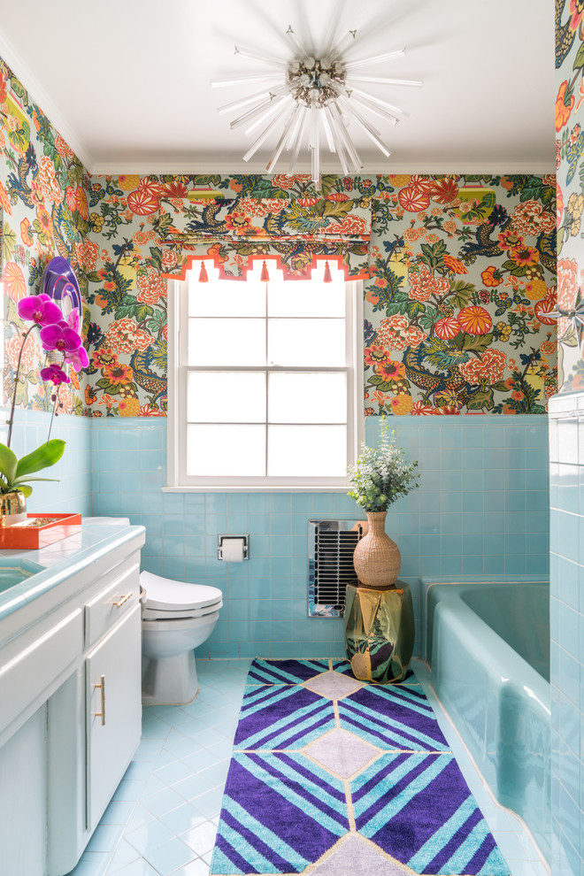 Photo of a tropical bathroom in Los Angeles with flat-panel cabinets, white cabinets, an alcove tub, multi-coloured walls, tile benchtops, blue floor and blue benchtops.