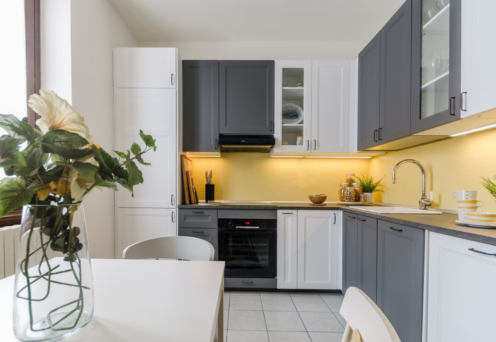 Inredning av ett modernt litet grå grått kök, med laminatbänkskiva, gult stänkskydd, integrerade vitvaror, klinkergolv i porslin, beiget golv, en enkel diskho, luckor med infälld panel och grå skåp