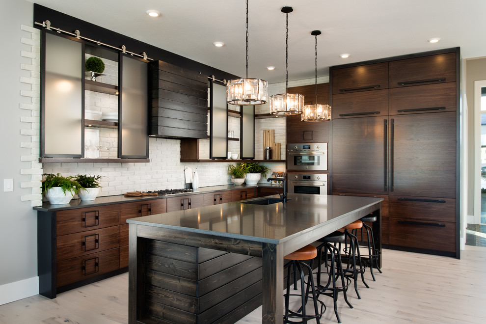 Inspiration for a large industrial l-shaped eat-in kitchen in Other with an undermount sink, flat-panel cabinets, dark wood cabinets, white splashback, brick splashback, panelled appliances, light hardwood floors, with island, beige floor and soapstone benchtops.