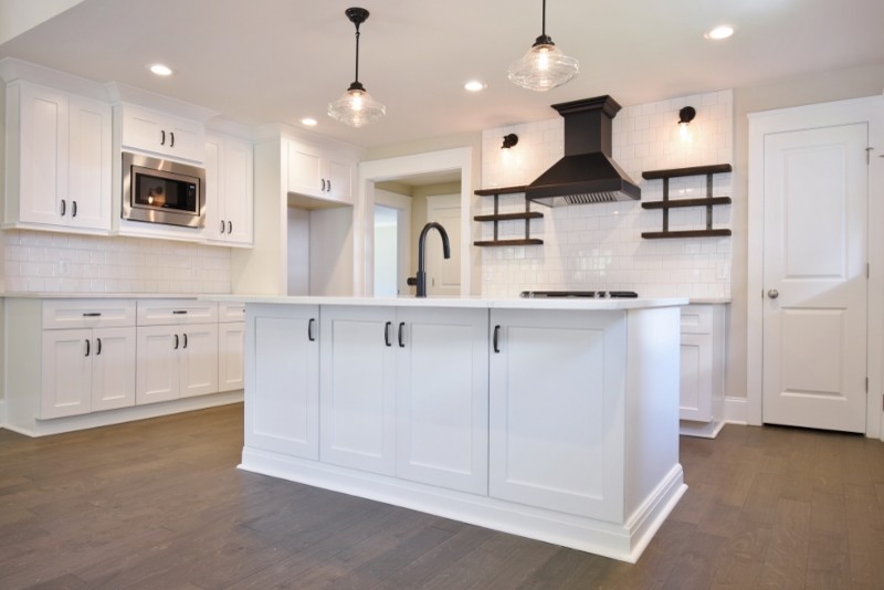 Photo of a mid-sized arts and crafts eat-in kitchen in Atlanta with shaker cabinets, white cabinets, white splashback, subway tile splashback, stainless steel appliances, medium hardwood floors, with island, brown floor, white benchtop, an undermount sink and quartz benchtops.